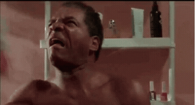 Shirtless Man Crying In Bathroom Next To Perfume Shelf GIF