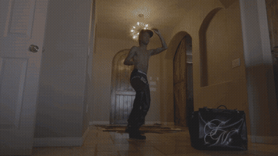 Shirtless Man Dancing Next To Bag Saying GM GIF