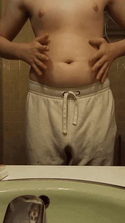 Shirtless Man Holding Belly At Bathroom Sink GIF