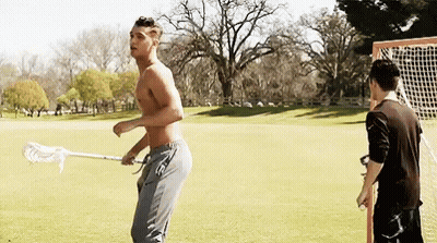 Shirtless Man Holding Lacrosse Stick With Another Man Behind