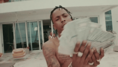 Shirtless Man Holding Stack Of Money In Front Of Large House GIF