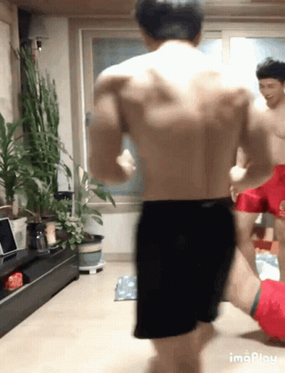 Shirtless Man In Black Shorts Standing With Plants GIF
