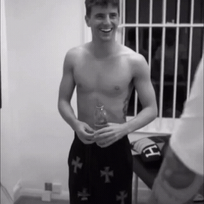 Shirtless Man In Black Shorts With Crosses Smiling GIF