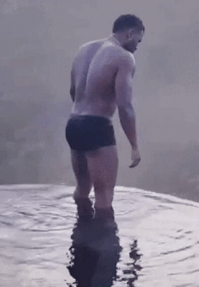 Shirtless Man In Black Trunks Standing In Water GIF