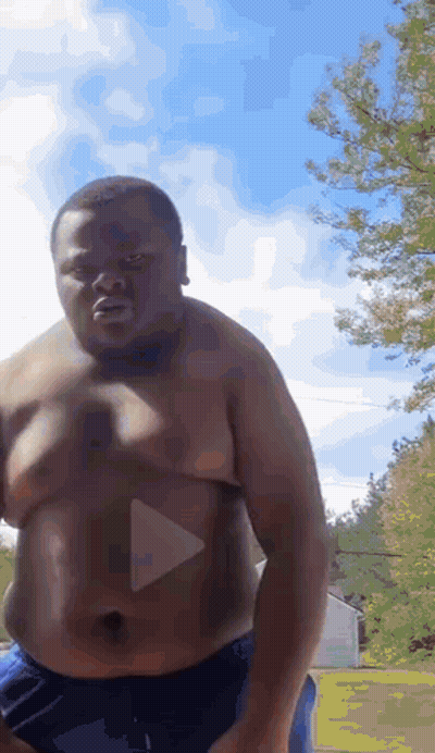 Shirtless Man In Blue Shorts Standing In Front Of Trees GIF