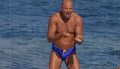 Shirtless Man In Blue Swim Trunks Jumping Into Ocean GIF