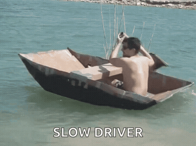 Shirtless Man In Cardboard Boat Saying Slow Driver GIF