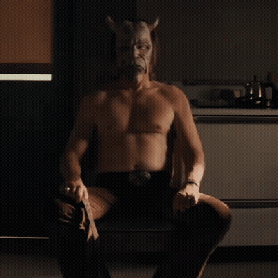 Shirtless Man In Devil Mask Sitting On Chair GIF