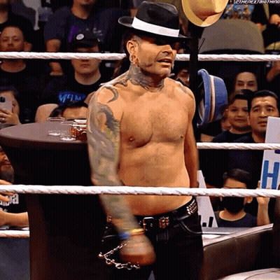 Shirtless Man In Fedora In Wrestling Ring With Sign Saying H GIF