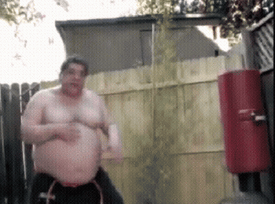 Shirtless Man in Front of Fence and Water Cooler