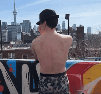 Shirtless Man In Front Of Graffiti Wall Saying N GIF