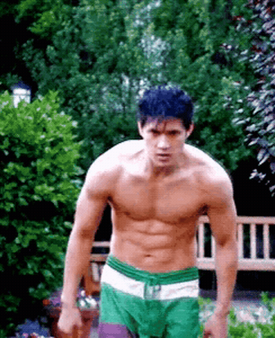Shirtless Man In Green Shorts Standing In Garden GIF