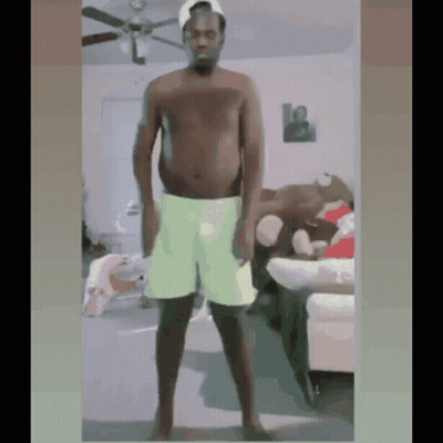 Shirtless Man In Green Shorts Standing In Living Room GIF