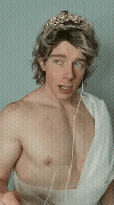 Shirtless Man In Laurel Wreath And White Robe GIF