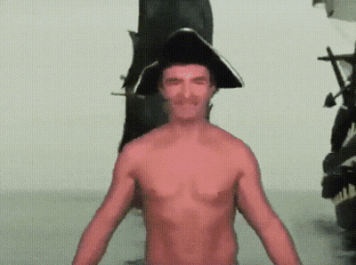 Shirtless Man In Pirate Hat In Front Of Statue GIF