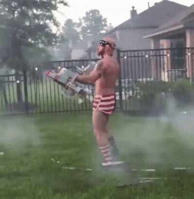 Shirtless Man In Red White And Blue Shorts Holding Flamethrower GIF