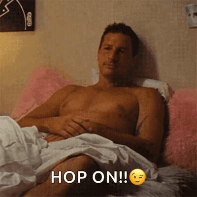 Shirtless Man Laying In Bed Saying Hop On GIF