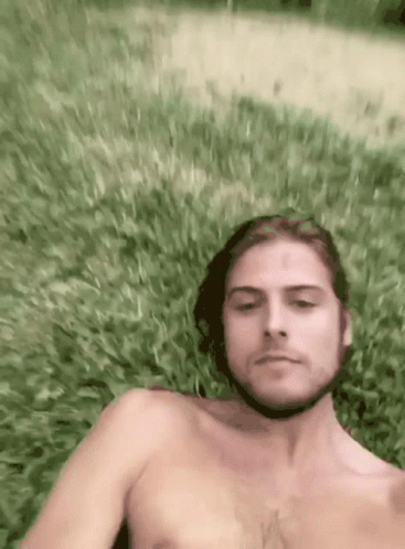 Shirtless Man Laying In Grass Looking At Camera GIF