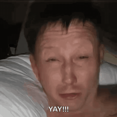 Shirtless Man Laying On Bed Saying Yay GIF