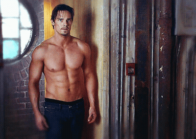 Shirtless Man Leaning Against Red Wall GIF