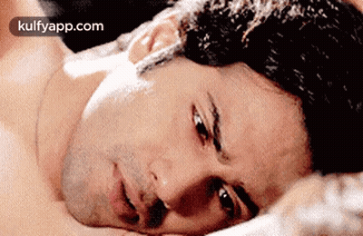 Shirtless Man Lying On Bed Looking At Camera GIF