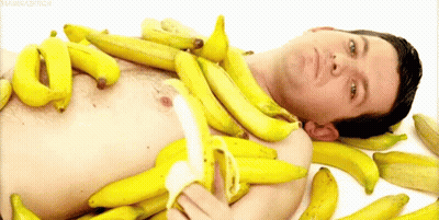 Shirtless Man Lying On Pile Of Bananas GIF