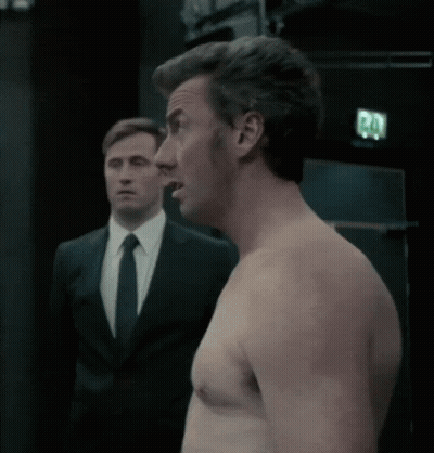 Shirtless Man Next to Man in Suit and Tie