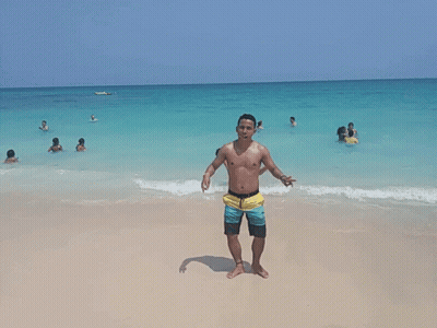 Shirtless Man On Beach Giving Peace Sign GIF