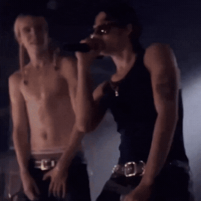 Shirtless Man Singing Into Microphone Next To Another Man GIF