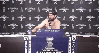 Shirtless Man Sitting At Table With Stanley Cup Sign GIF