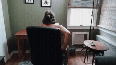 Shirtless Man Sitting In Living Room Chair GIF