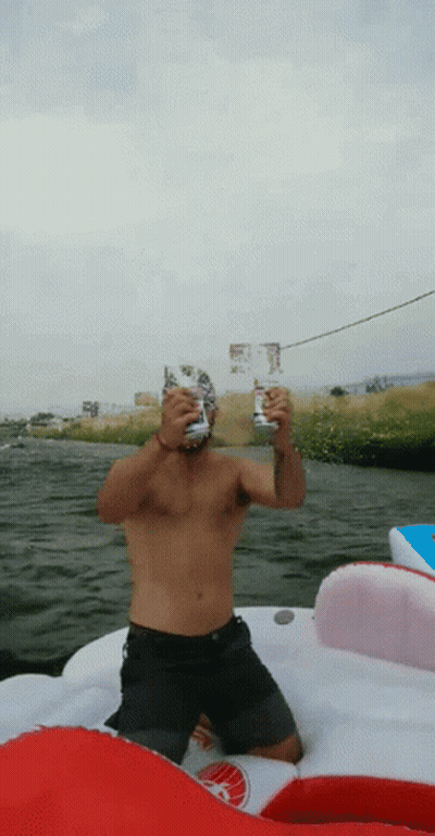 Shirtless Man Sitting On Boat Holding Two Cans GIF