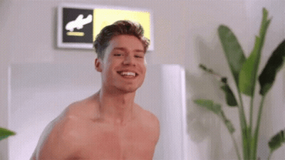 Shirtless Man Smiling Next To Runway Sign GIF