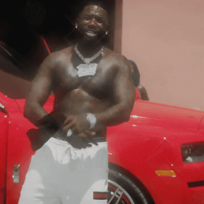 Shirtless Man Standing by Red Car With Open Door