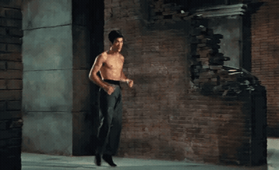 Shirtless Man Standing In Front Of Brick Wall GIF