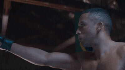 Shirtless Man Standing In Front Of Flag With Letter O GIF