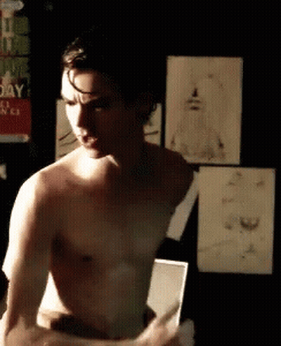 Shirtless Man Standing In Front Of Mirror In Dark Room GIF