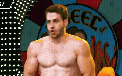 Shirtless Man Standing In Front Of Wheel GIF