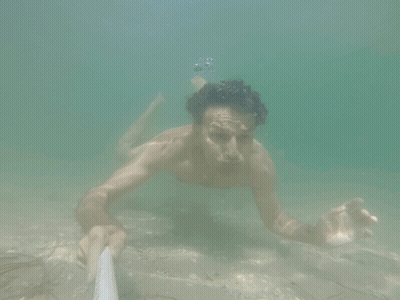 Shirtless Man Swimming Underwater Holding Rope GIF