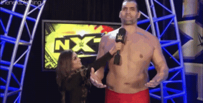 Shirtless Man Talking Into Microphone With Woman Behind Him GIF