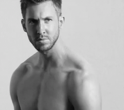 Shirtless Man With Arm Tattoo Sitting Cross-Legged GIF