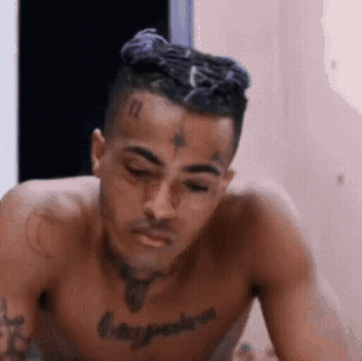 Shirtless Man With Chest Tattoo Sitting Eyes Closed GIF