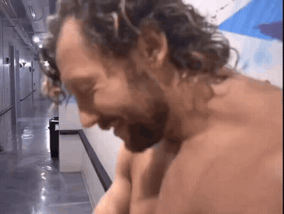 Shirtless Man With Curly Hair Sitting In Hallway GIF