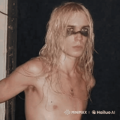 Shirtless Man With Long Blonde Hair And Black Eye Standing Next To Door GIF