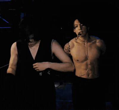 Shirtless Man With Microphone Next To Another Man GIF