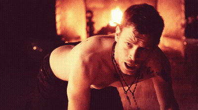 Shirtless Man With Necklace Crawling in Front of Fire