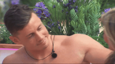 Shirtless Man With Necklace Smiling At Woman GIF