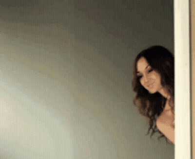 Shirtless Woman Peeking From Doorway Smiling GIF