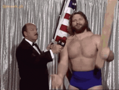 Shirtless Wrestler Holding Flag Interviewed By Tuxedo Man GIF