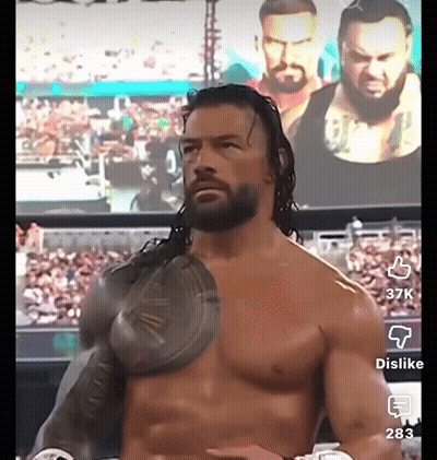 Shirtless Wrestler In Front Of Roman Reigns Screen GIF